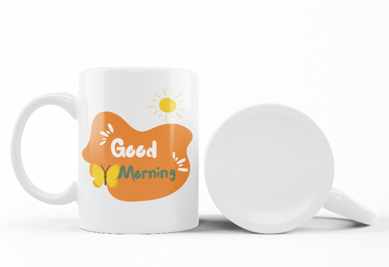 Two ceramic mugs with nature-inspired designs. One mug displays a colorful forest scene with trees and the sun, while the other mug has a 'Good Morning' message with a sun and coffee-related graphics.