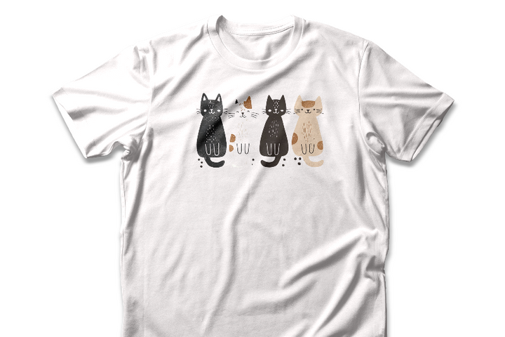 A white t-shirt featuring a graphic design of four cute cats in a lineup, each in different colors such as black, white, brown, and tan.