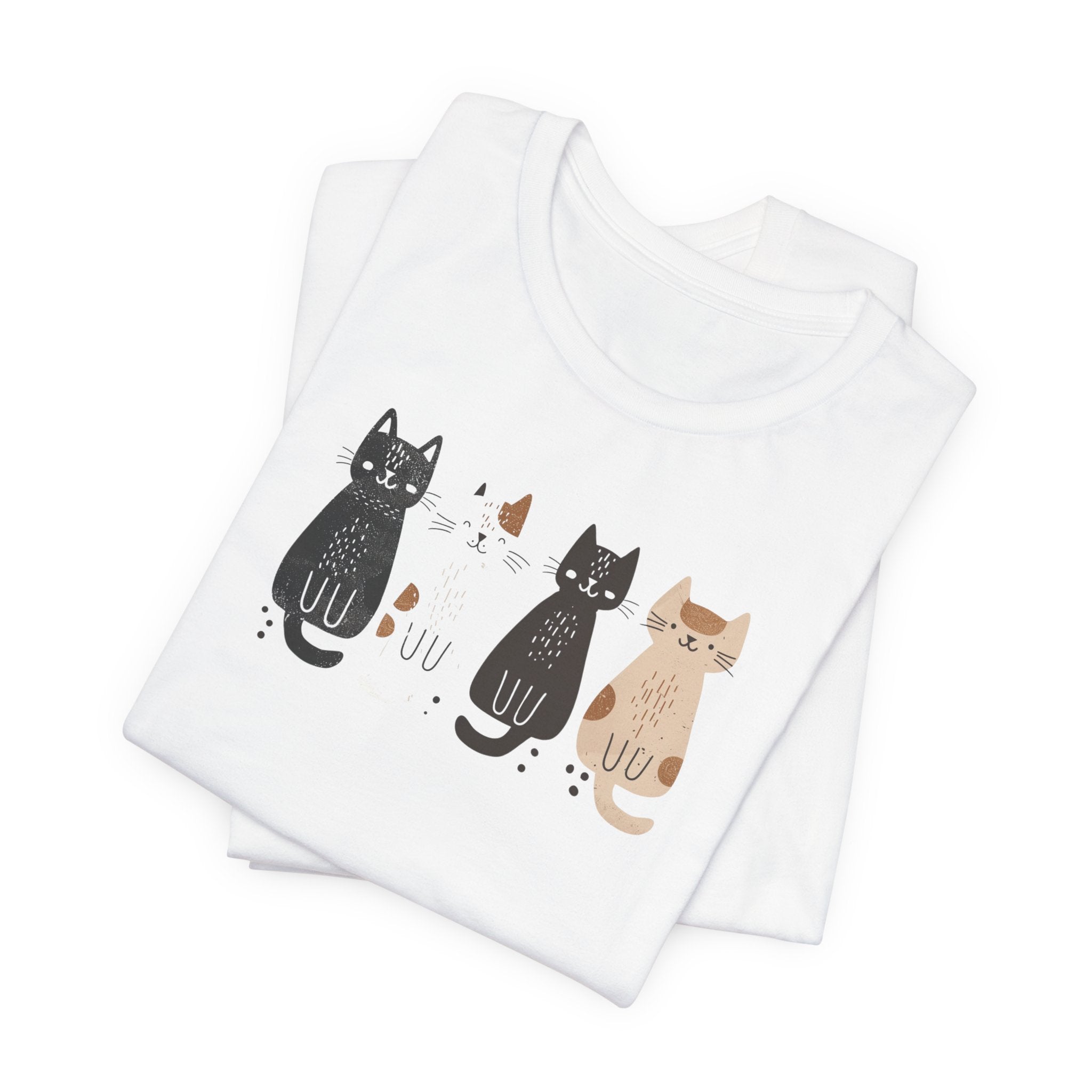 A white t-shirt featuring a graphic design of four cute cats in a lineup, each in different colors such as black, white, brown, and tan.
