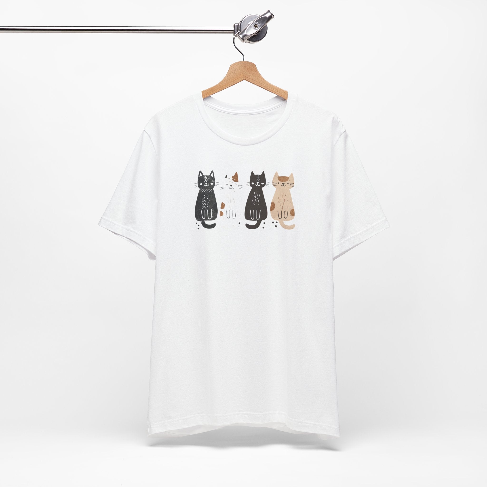 A white t-shirt featuring a graphic design of four cute cats in a lineup, each in different colors such as black, white, brown, and tan.