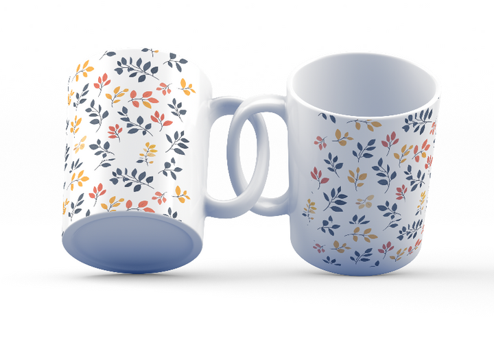 A set of two ceramic coffee mugs with a floral and autumn leaf design on a white background, one mug is filled with a liquid, possibly coffee or tea.