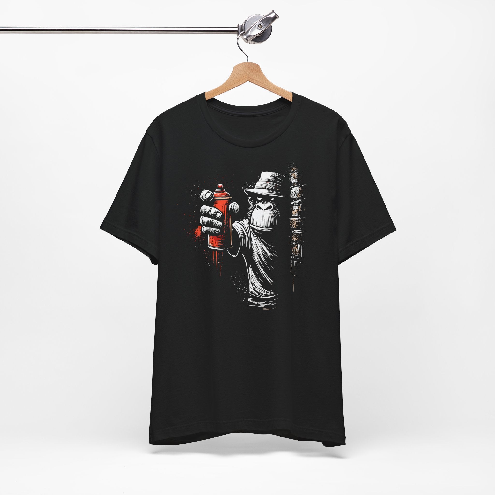 Black t-shirt with graphic design of a person holding a spray can on a hanger against a white background