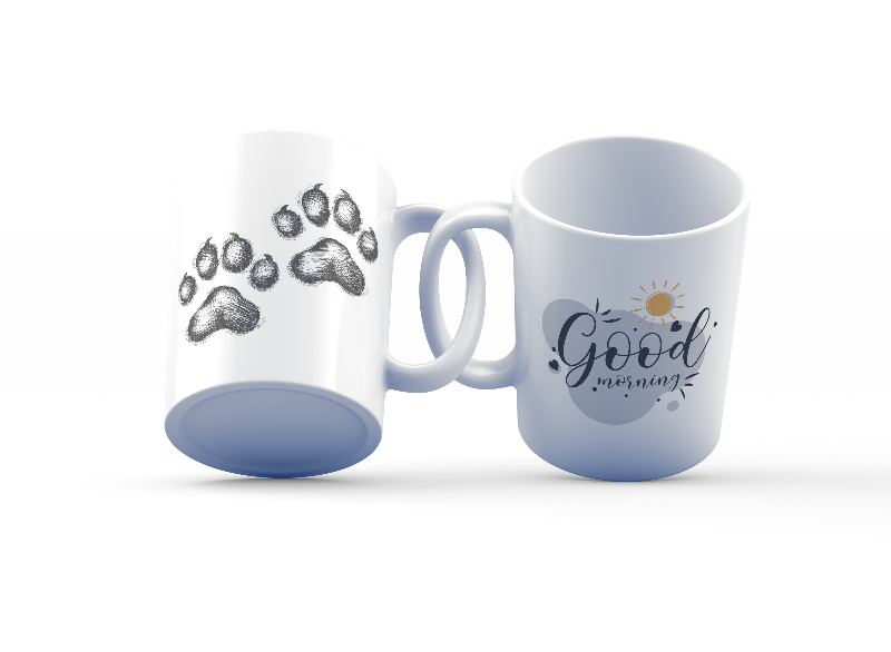 A set of two ceramic mugs, one with a black paw print design on a white background and the other with a 'Good Morning' message alongside a sun and paw accent on a blue background.