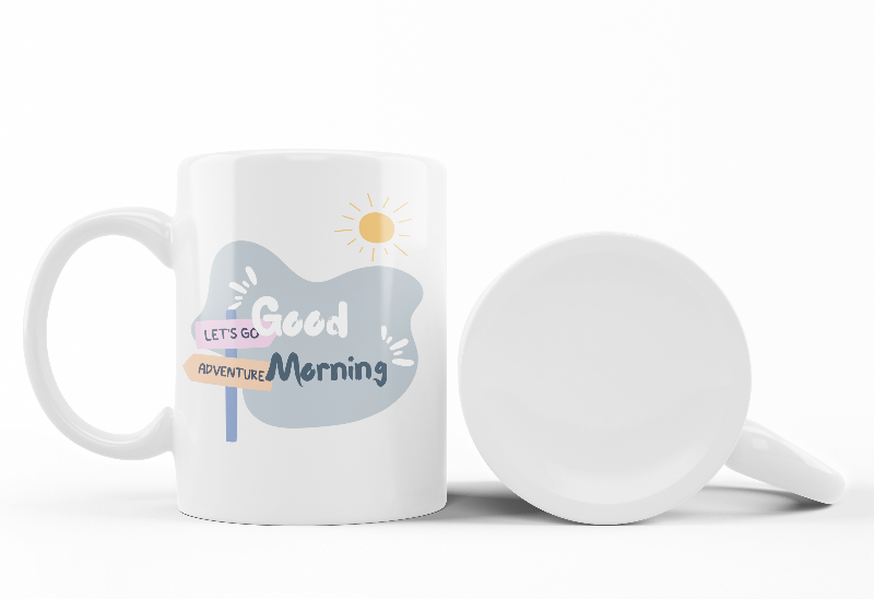 A set of two ceramic mugs, one with an adventure theme featuring a hiker on a mountain, and the other with a 'Good Morning' message, both with a snowy mountain backdrop.