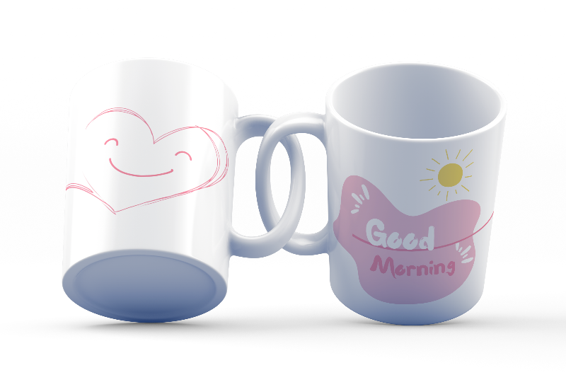 Two ceramic coffee mugs, one with a smiling heart design on the front and the other with a 'Good Morning' message alongside a sun graphic on the front. Both mugs have a white background with text and heart illustrations.