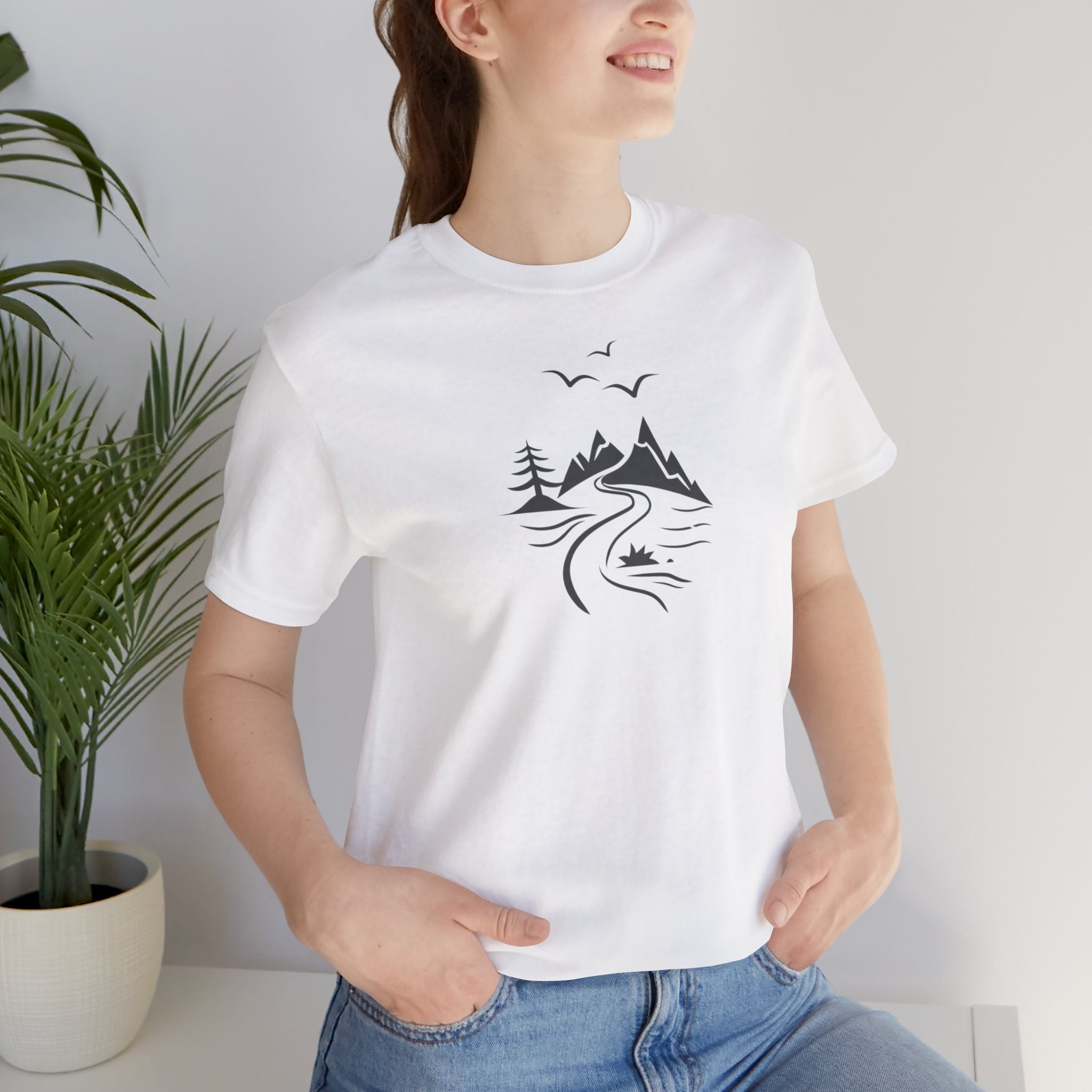 A white t-shirt featuring a minimalist black-and-white illustration of a mountain range, a river, and birds.