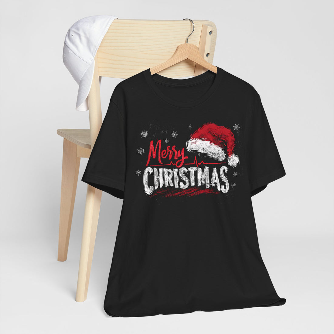 Black t-shirt with 'Merry Christmas' and Santa hat graphic on a wooden chair.