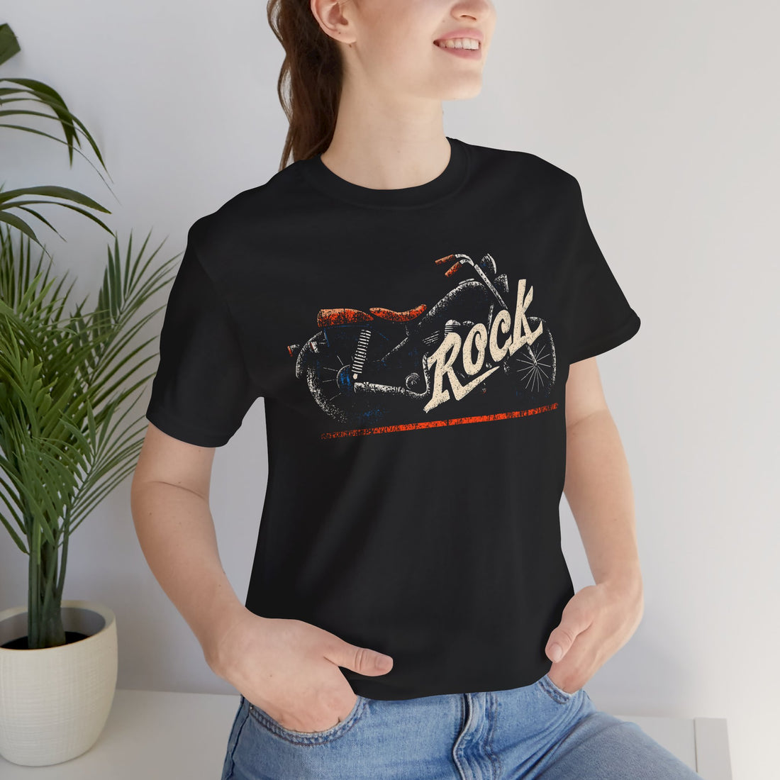 Person wearing a black t-shirt with a graphic design and the word 'Rock' in a casual setting.