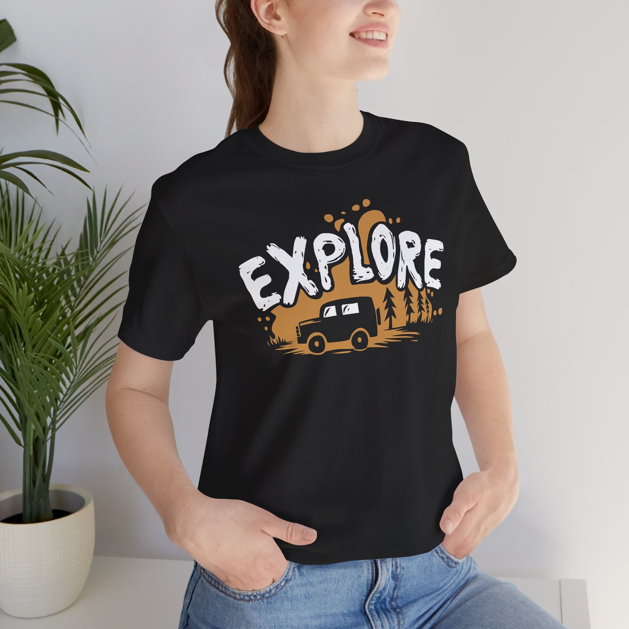 Person wearing a black t-shirt with 'EXPLORE' and a car graphic, standing indoors.