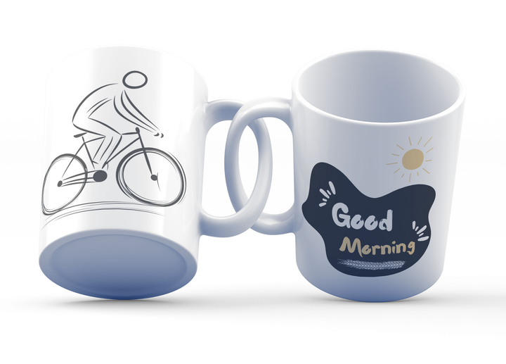 Two white ceramic mugs, one with a minimalist black bicycle design and the other featuring a 'Good Morning' message with a yellow sun accent, both with bold black and yellow prints.