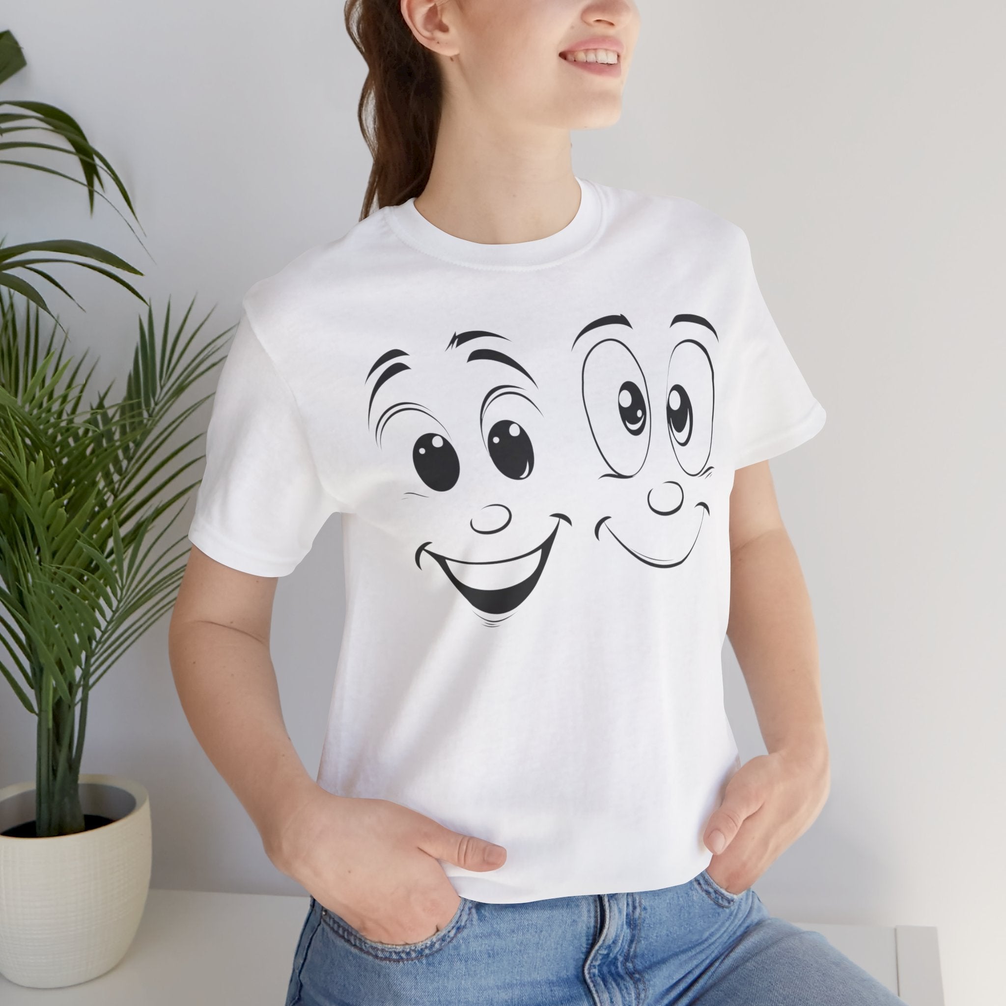 A white cotton tee with a graphic print of two cartoon faces with smiles on it.