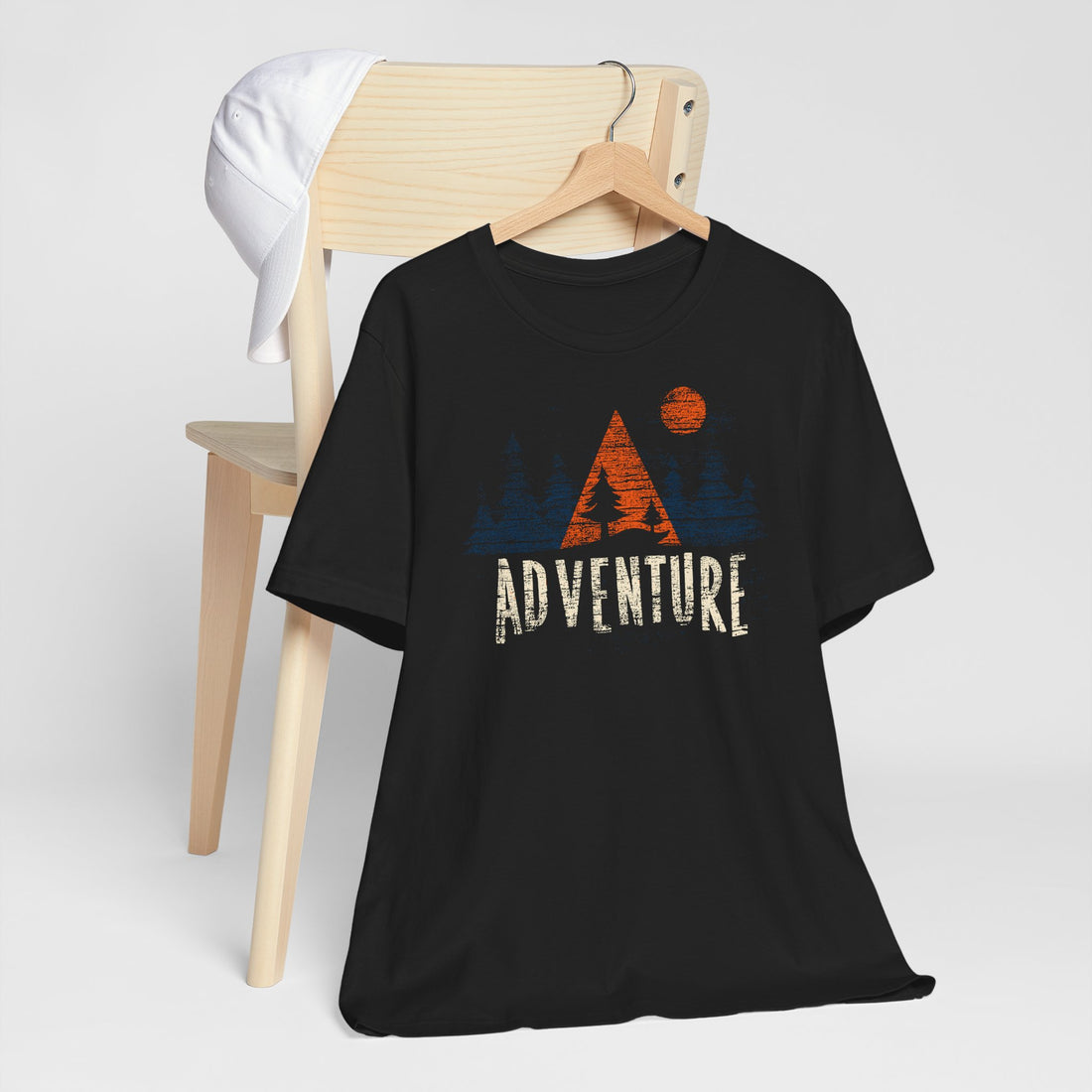 Black t-shirt with 'ADVENTURE' graphic design on a wooden chair against a white background