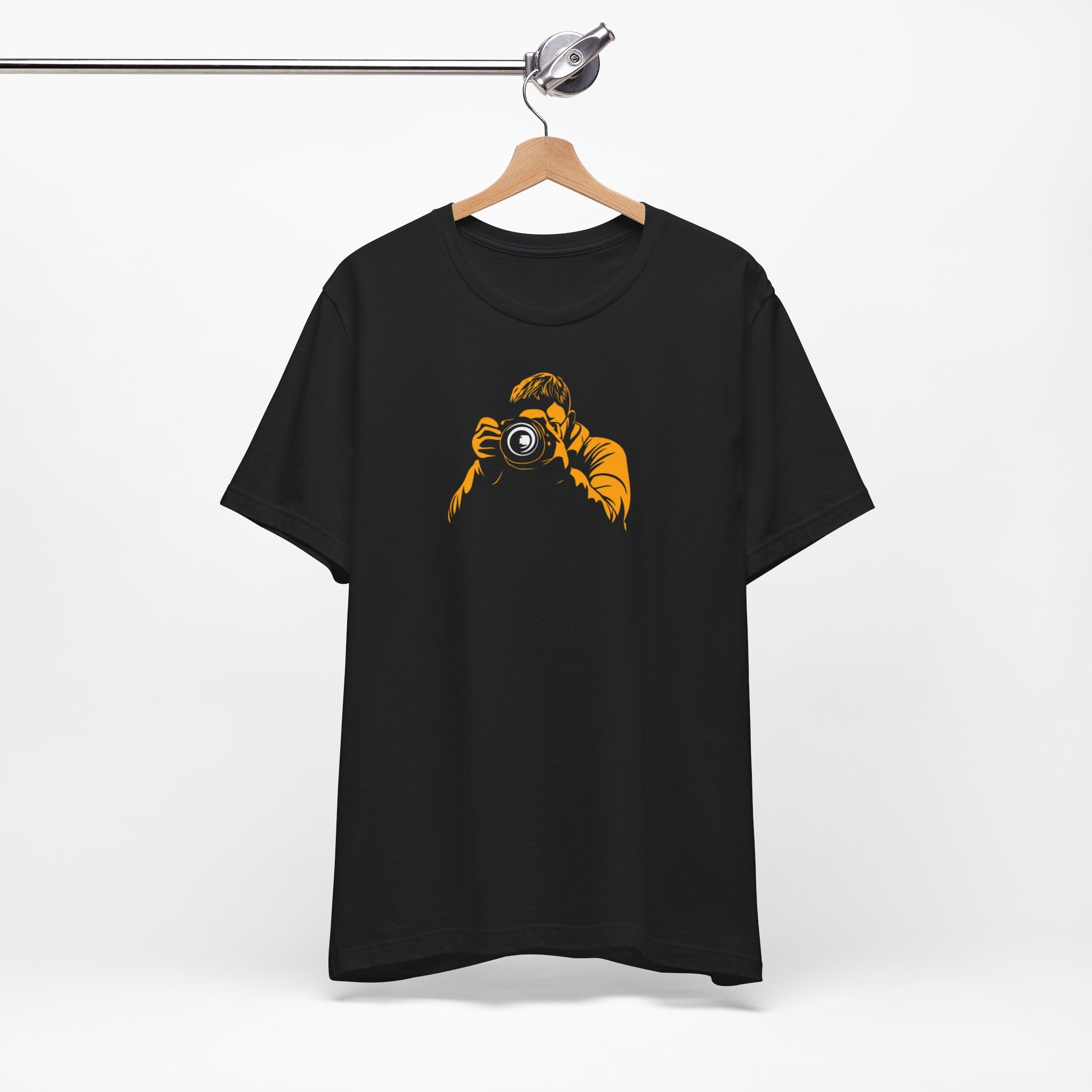 A black crew neck t-shirt with a bold yellow graphic of a photographer holding a camera.