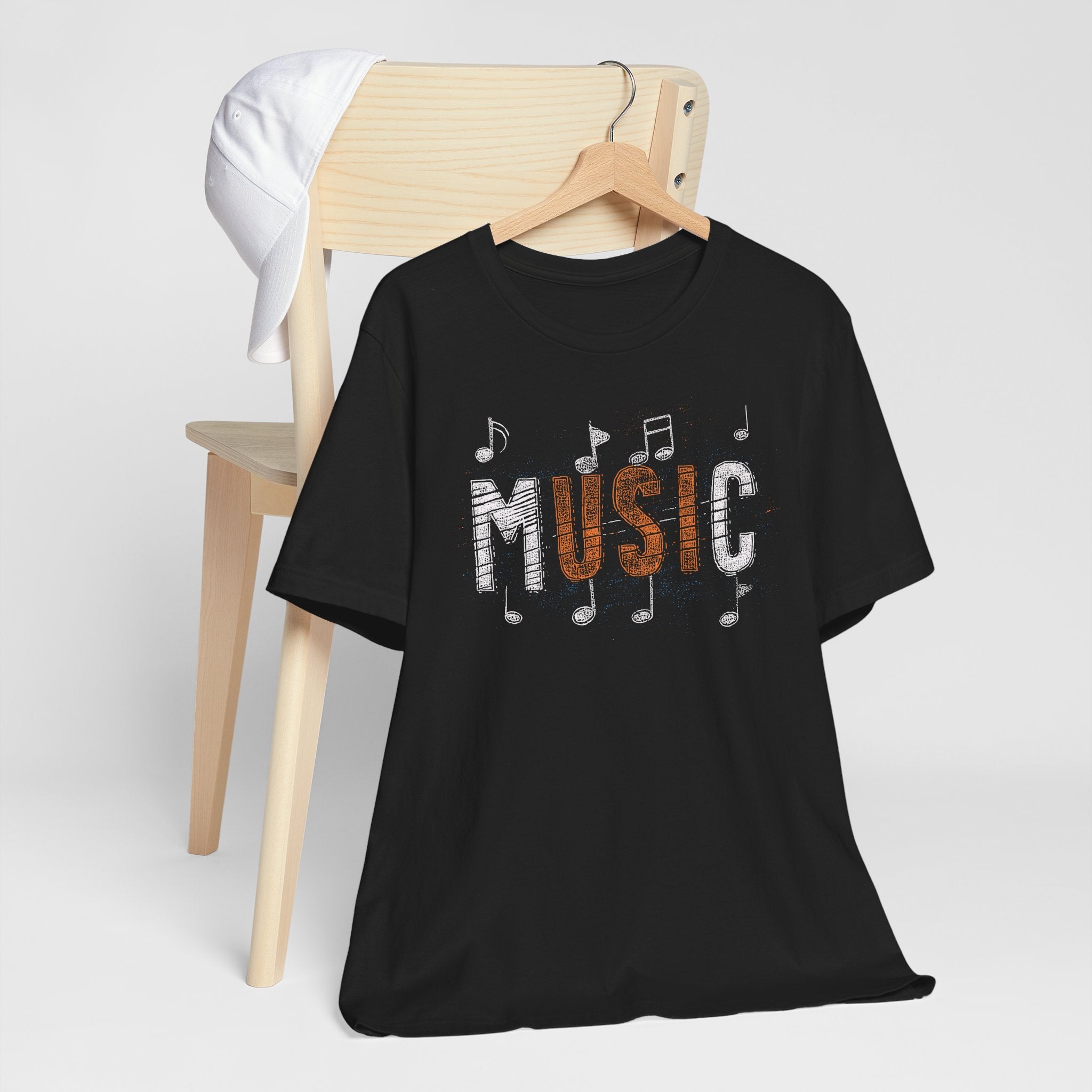 Black t-shirt with 'MUSIC' design on a hanger against a white background