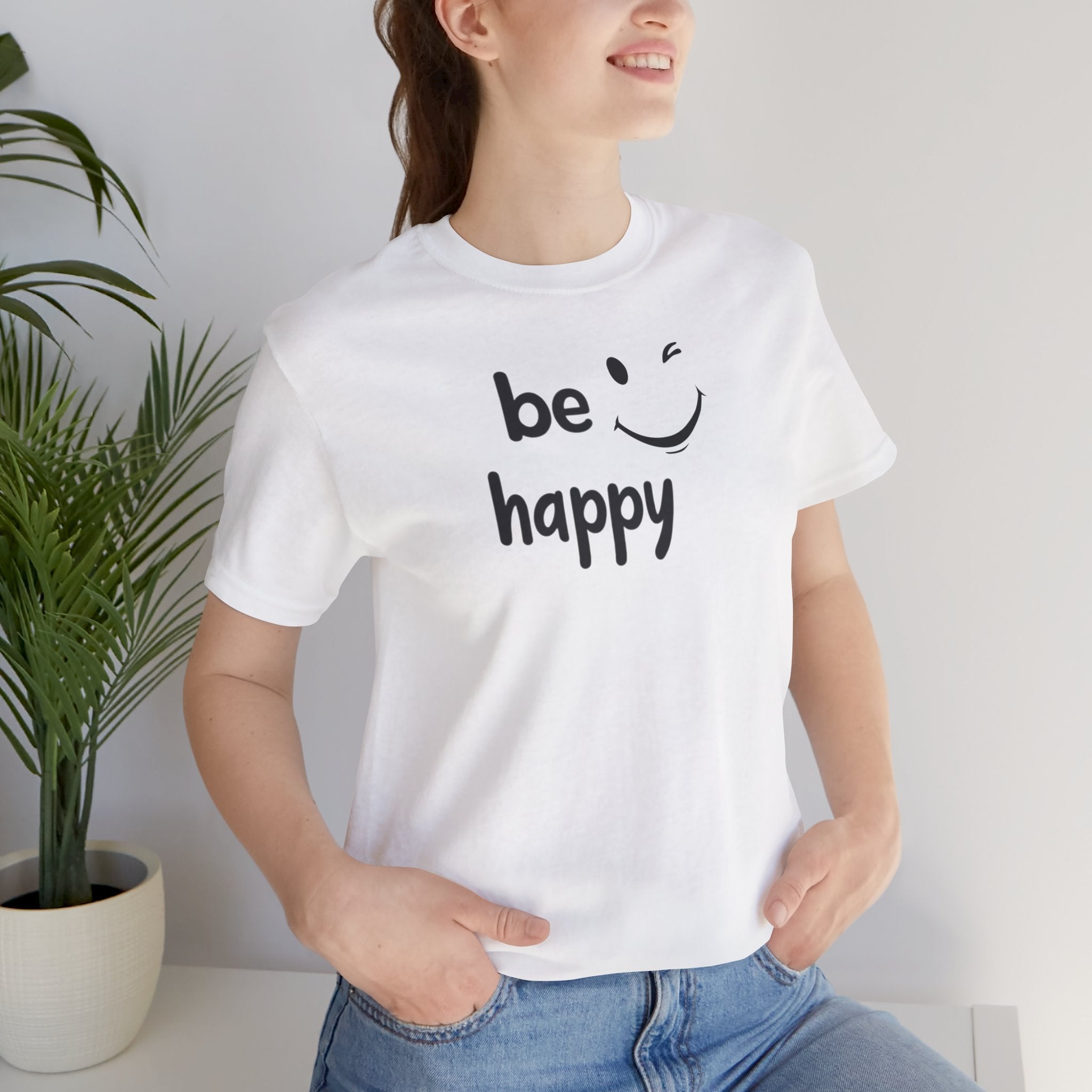 A black crew neck t-shirt with the text 'BE HAPPY' and a smiley face design on the front.