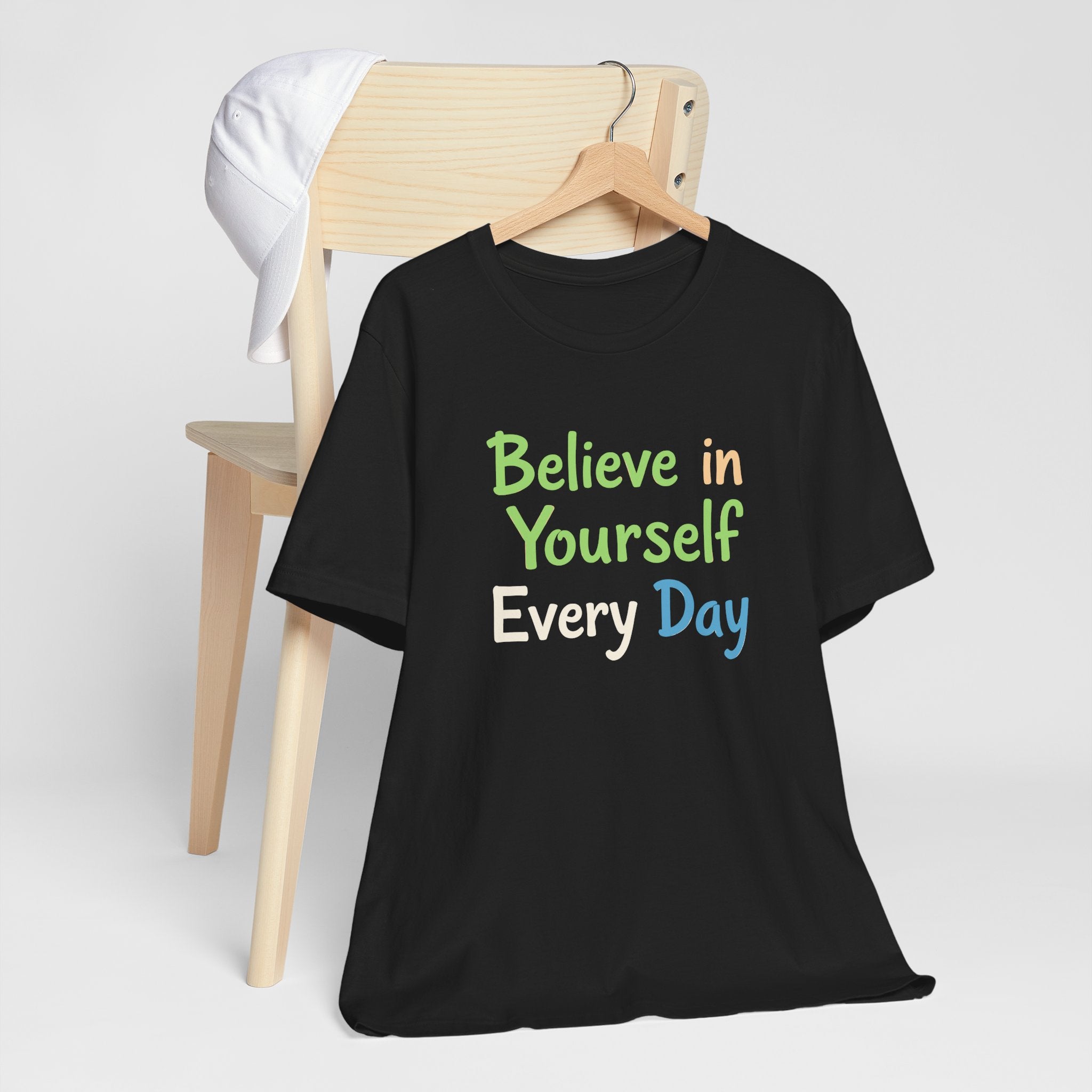 Black unisex t-shirt with the motivational phrase 'Believe in Yourself Every Day' printed in colorful typography.