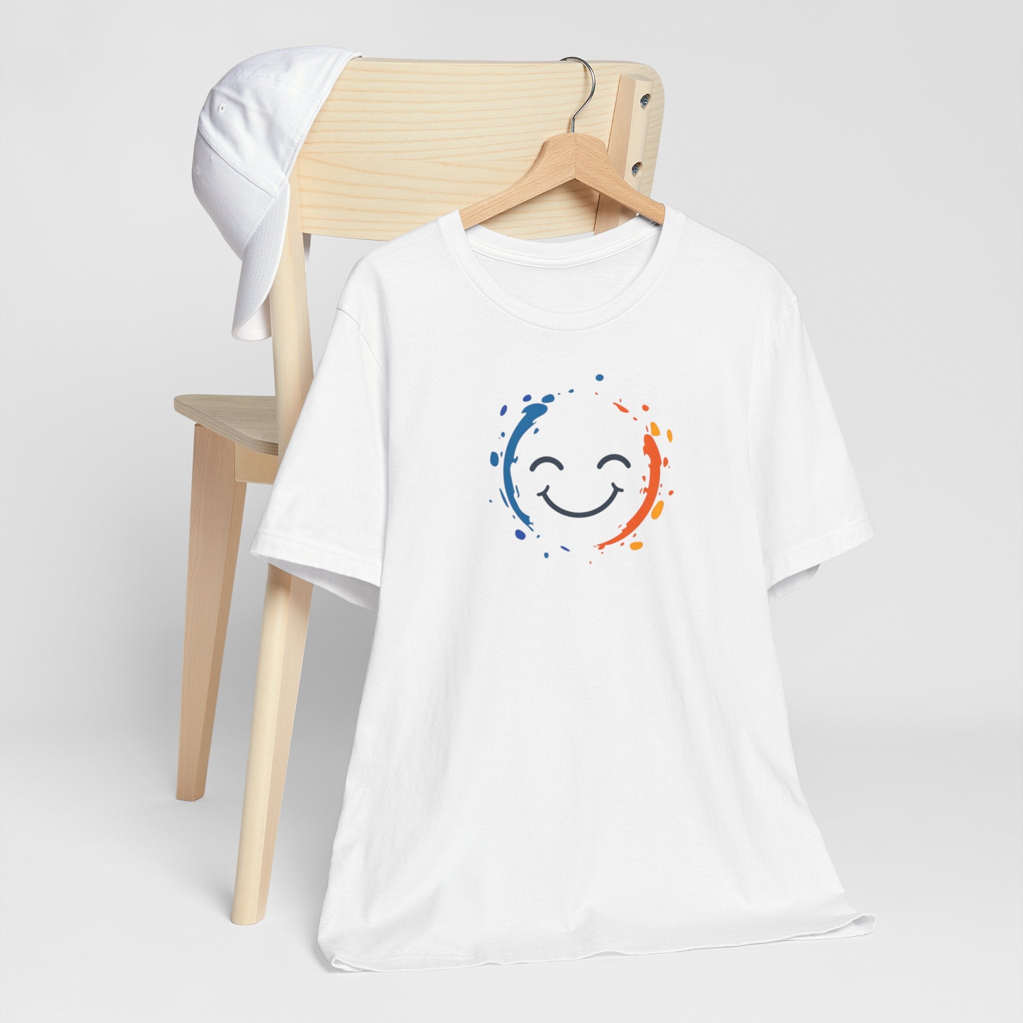 White cotton tee with a vibrant happy face design and color splashes in blue and orange.
