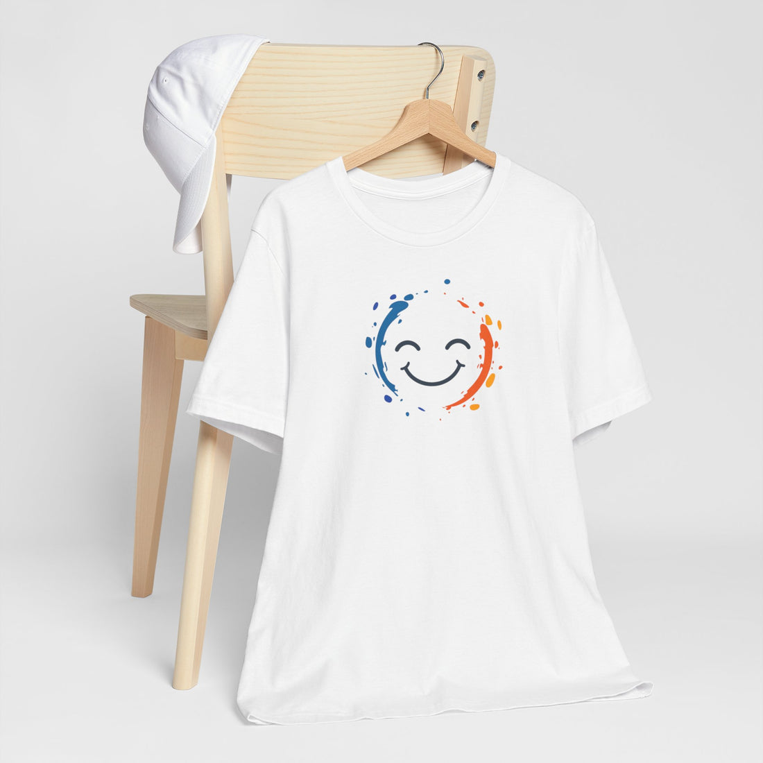 White cotton tee with a vibrant happy face design and color splashes in blue and orange.