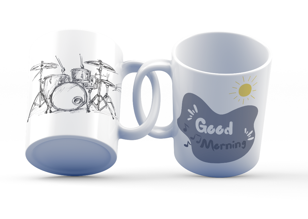 A white ceramic coffee cup with a hand-drawn sketch of a drum set on one side and a 'Good Morning' message with musical notes and a sun design on the other side.