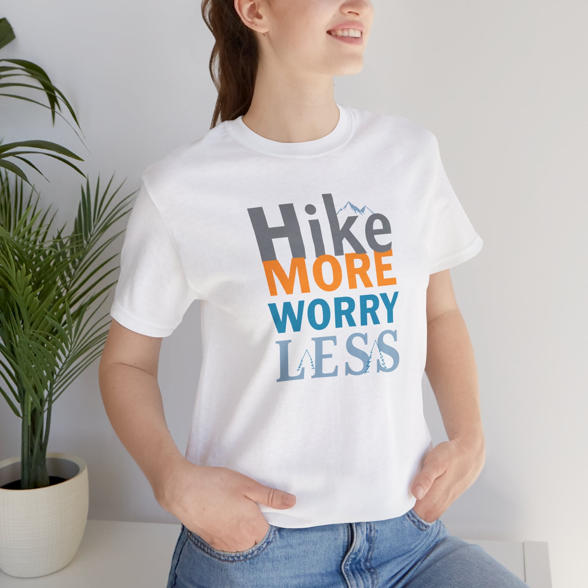 White crew neck t-shirt with the text 'Hike More Worry Less' printed in a gradient of orange, gray, and blue.