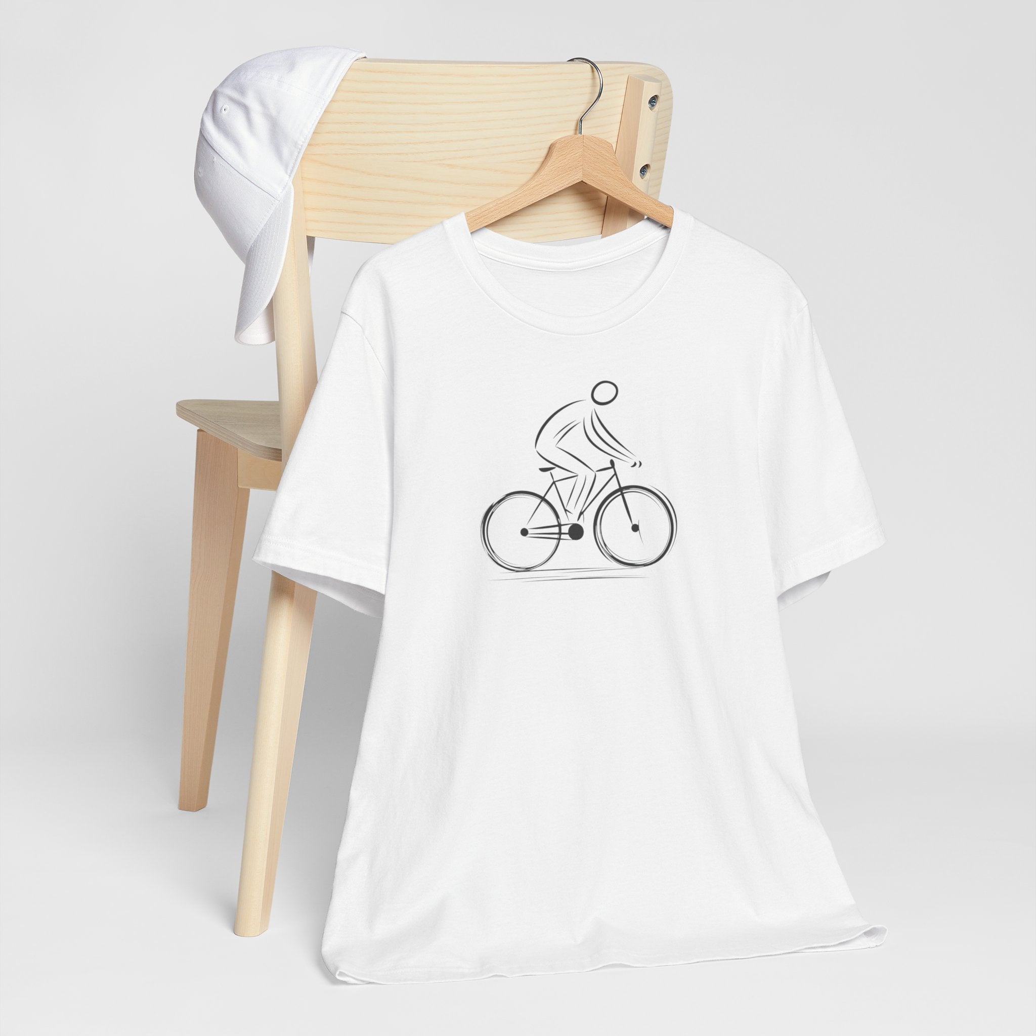 White cotton unisex t-shirt with a minimalist black line art design of a cyclist on a bicycle.