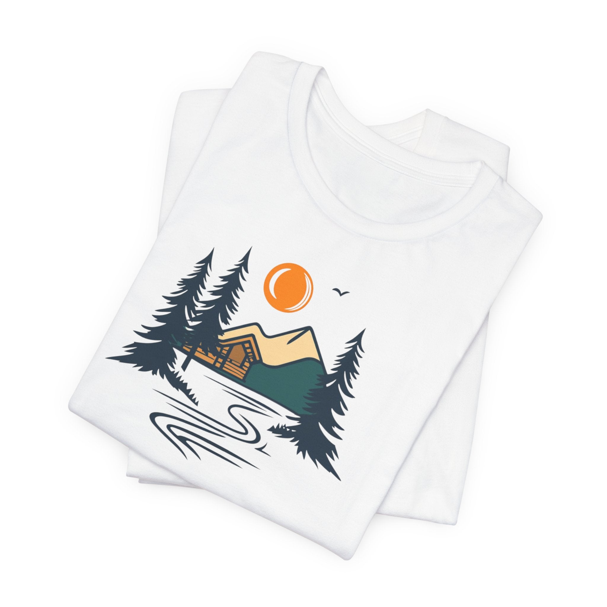 A white cotton t-shirt with a graphic design featuring a cabin, trees, and a mountain range with a warm orange sun.