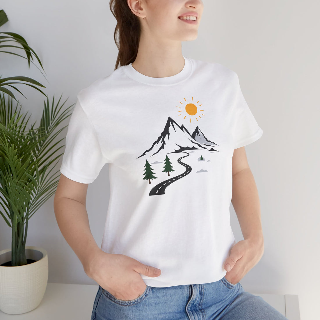 A white crew neck t-shirt with a graphic print of mountains, a winding road, and sun.