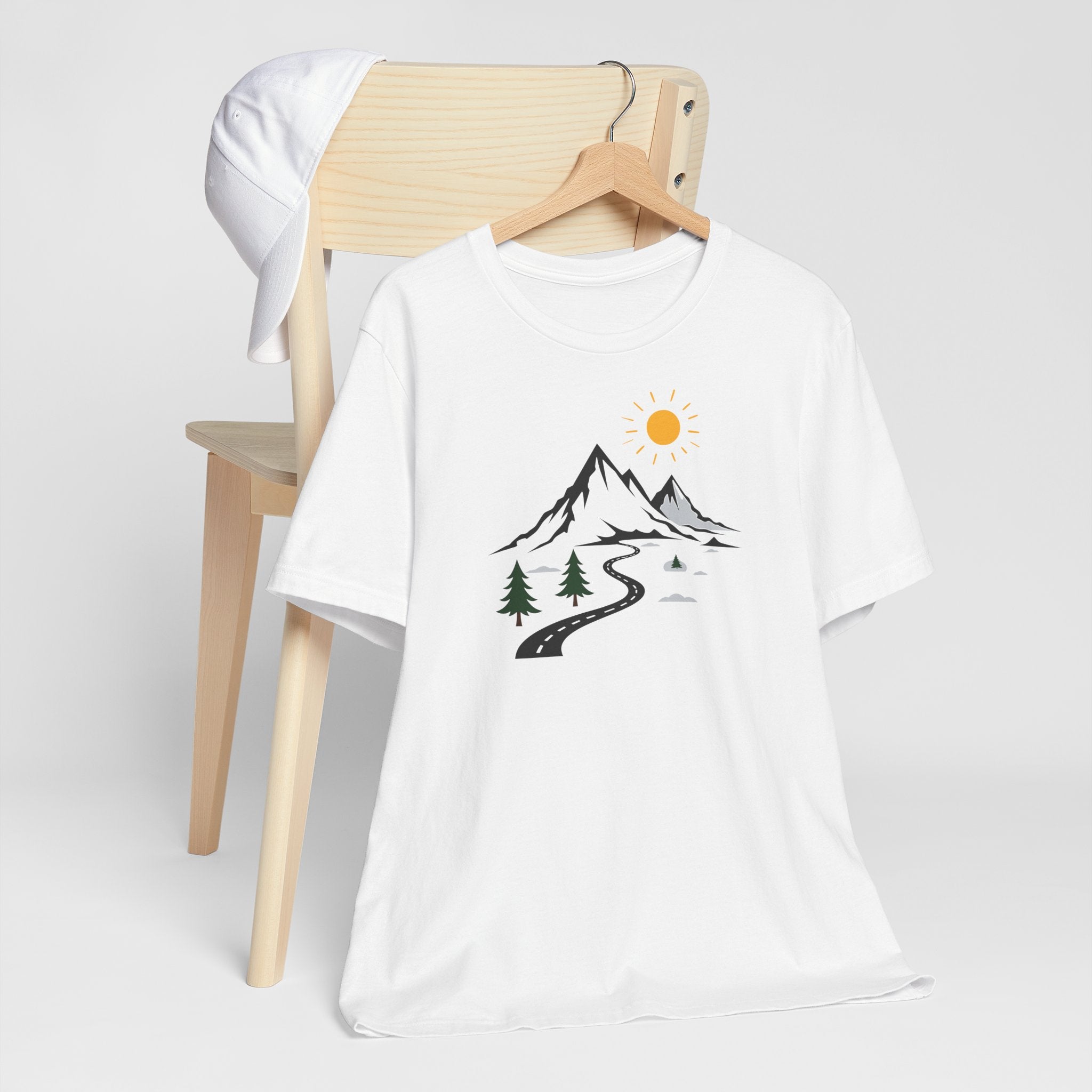 A white crew neck t-shirt with a graphic print of mountains, a winding road, and sun.