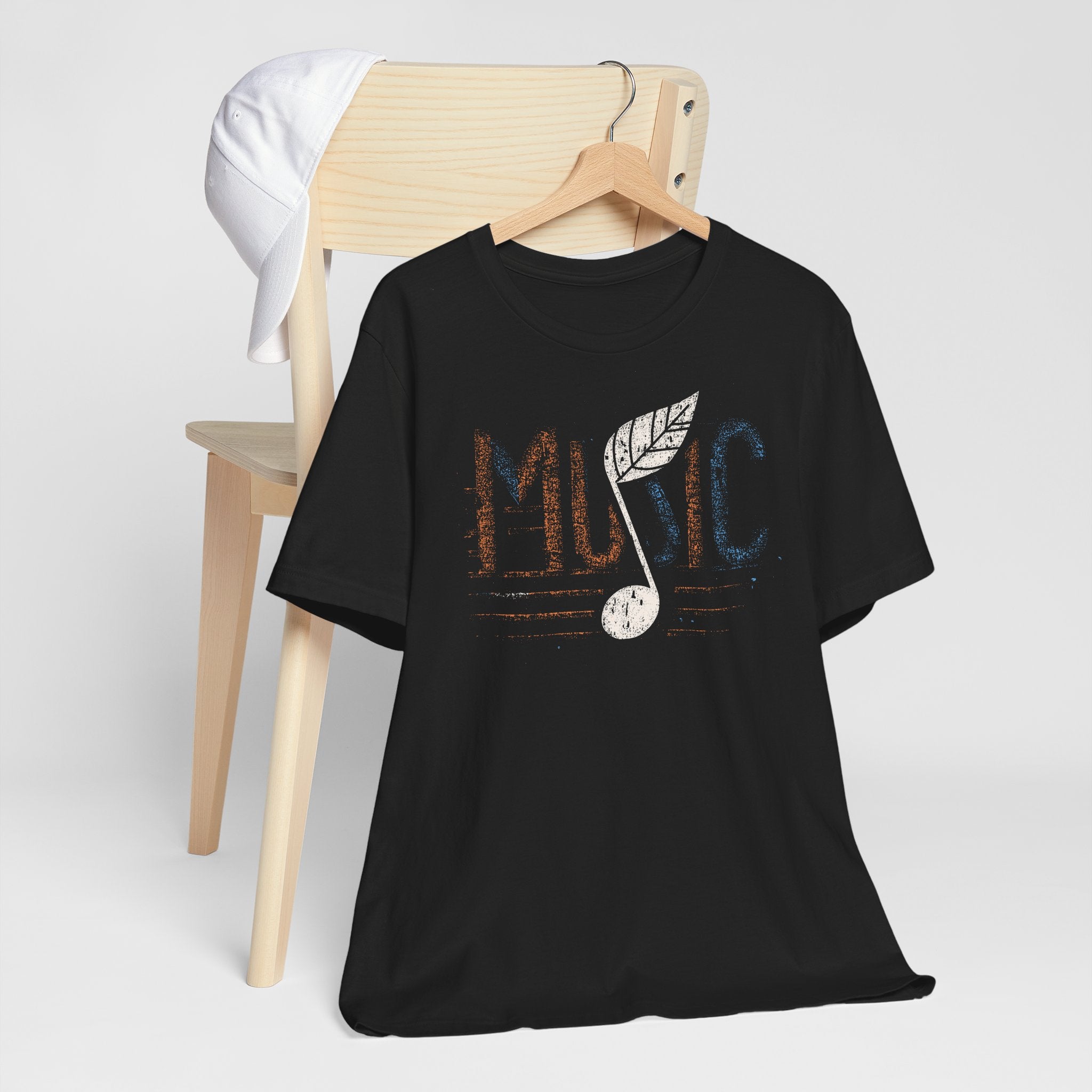 Black t-shirt with 'Music' design on a wooden chair against a white background