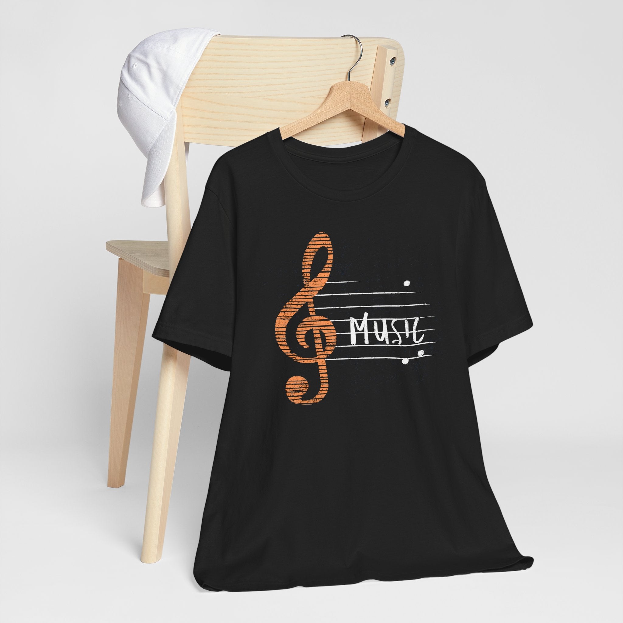 Black t-shirt with music-themed design on a wooden chair against a white background