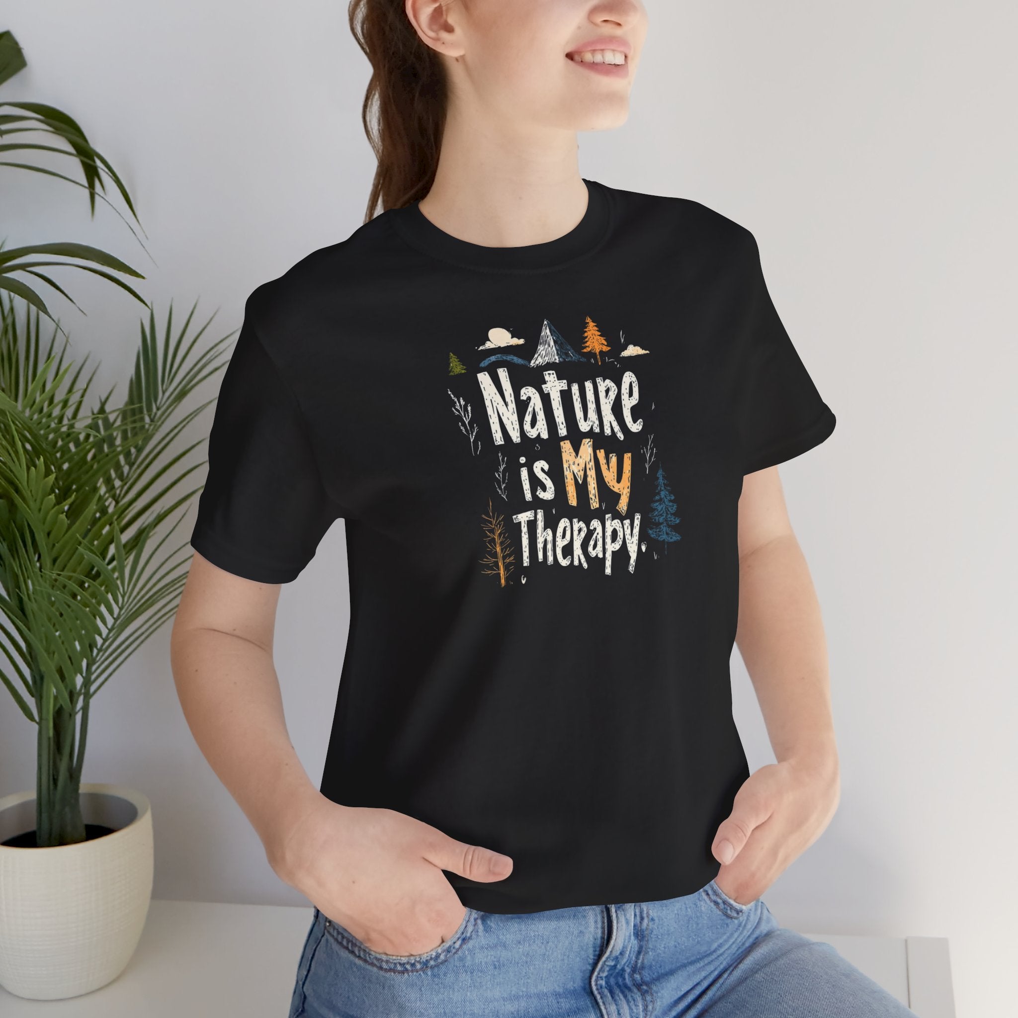 A black cotton t-shirt with a graphic design that includes mountains, trees, and the text 'Nature Is My Therapy'.