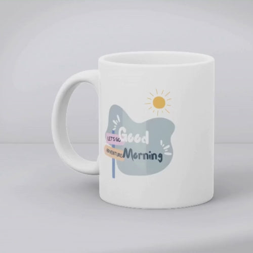 A set of two ceramic mugs, one with an adventure theme featuring a hiker on a mountain, and the other with a 'Good Morning' message, both with a snowy mountain backdrop.