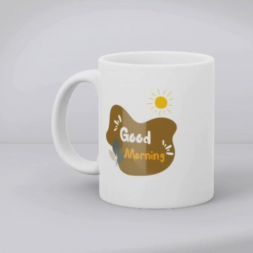 Two ceramic mugs side by side, one with a 'Good Morning' design and the other featuring a scenic nature landscape with trees and a sun rise.