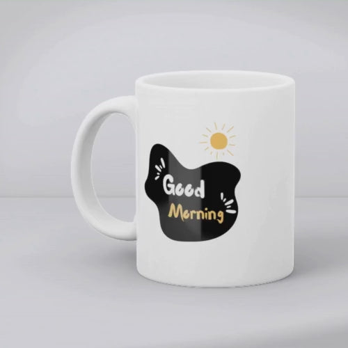 A glossy white ceramic mug with a mountain path design and a text 'GOOD MORNING' on the other side, placed against a plain background.