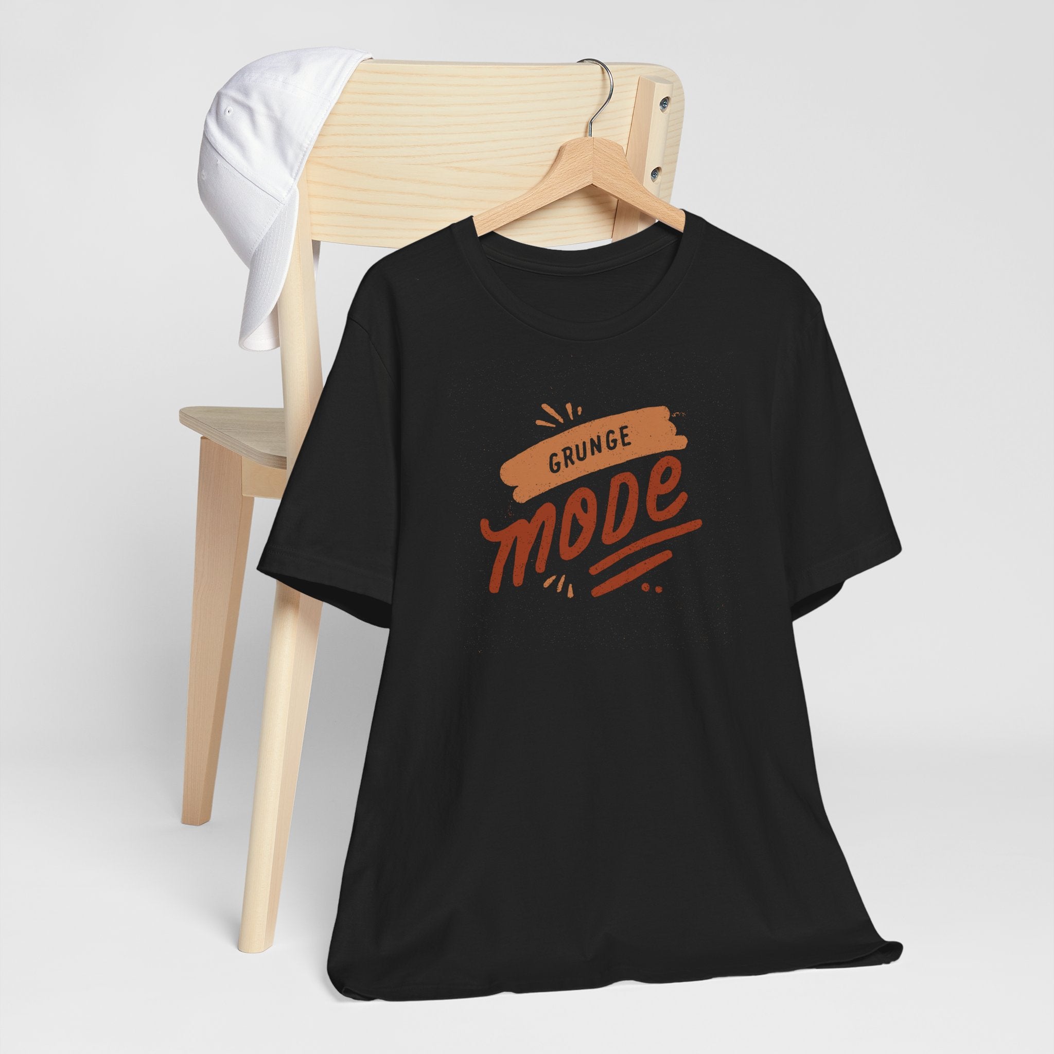 Black t-shirt with 'Grunge Mode' text on a wooden chair against a white background