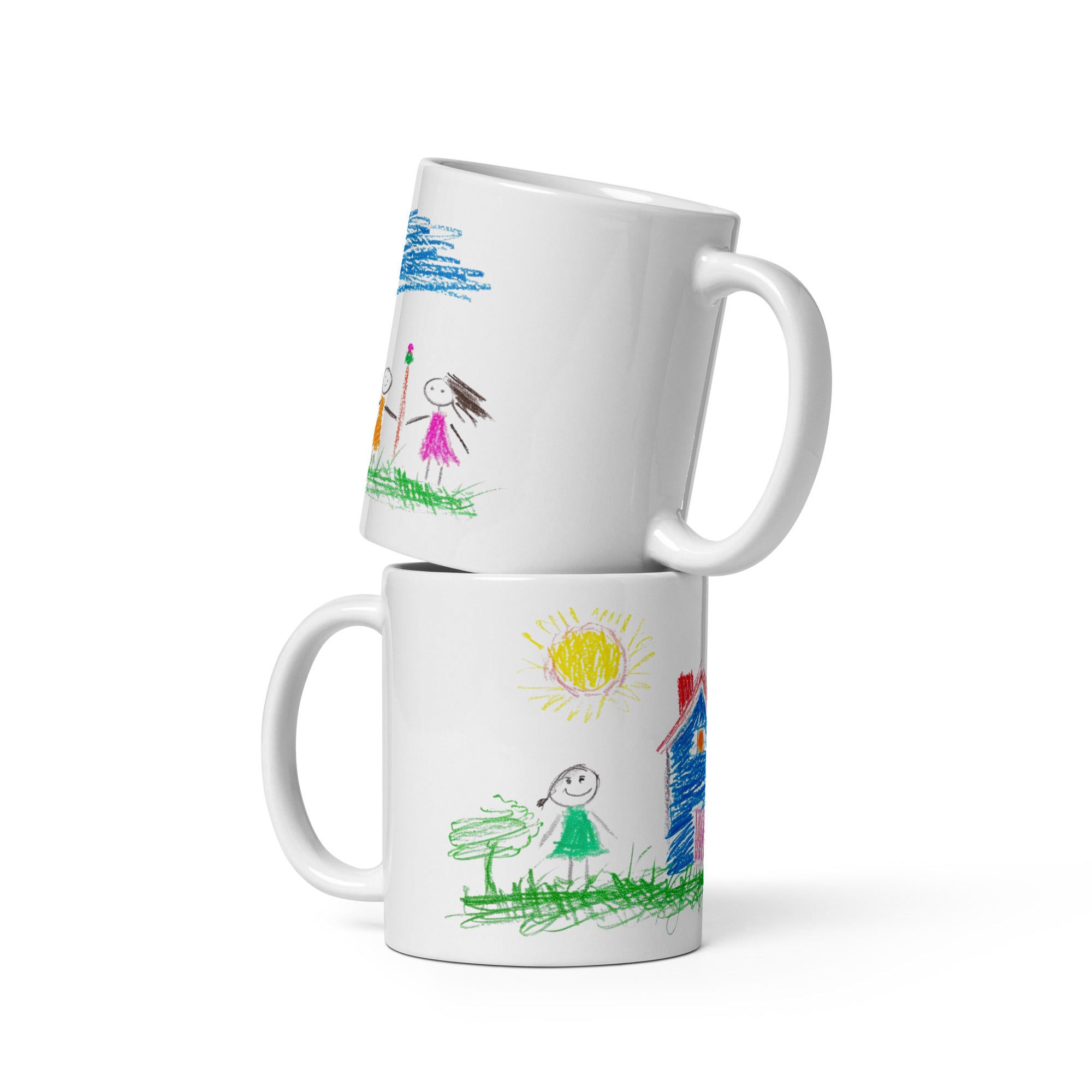 Two white ceramic mugs with colorful childlike drawings. One mug displays a house, sun, and a smiling family.