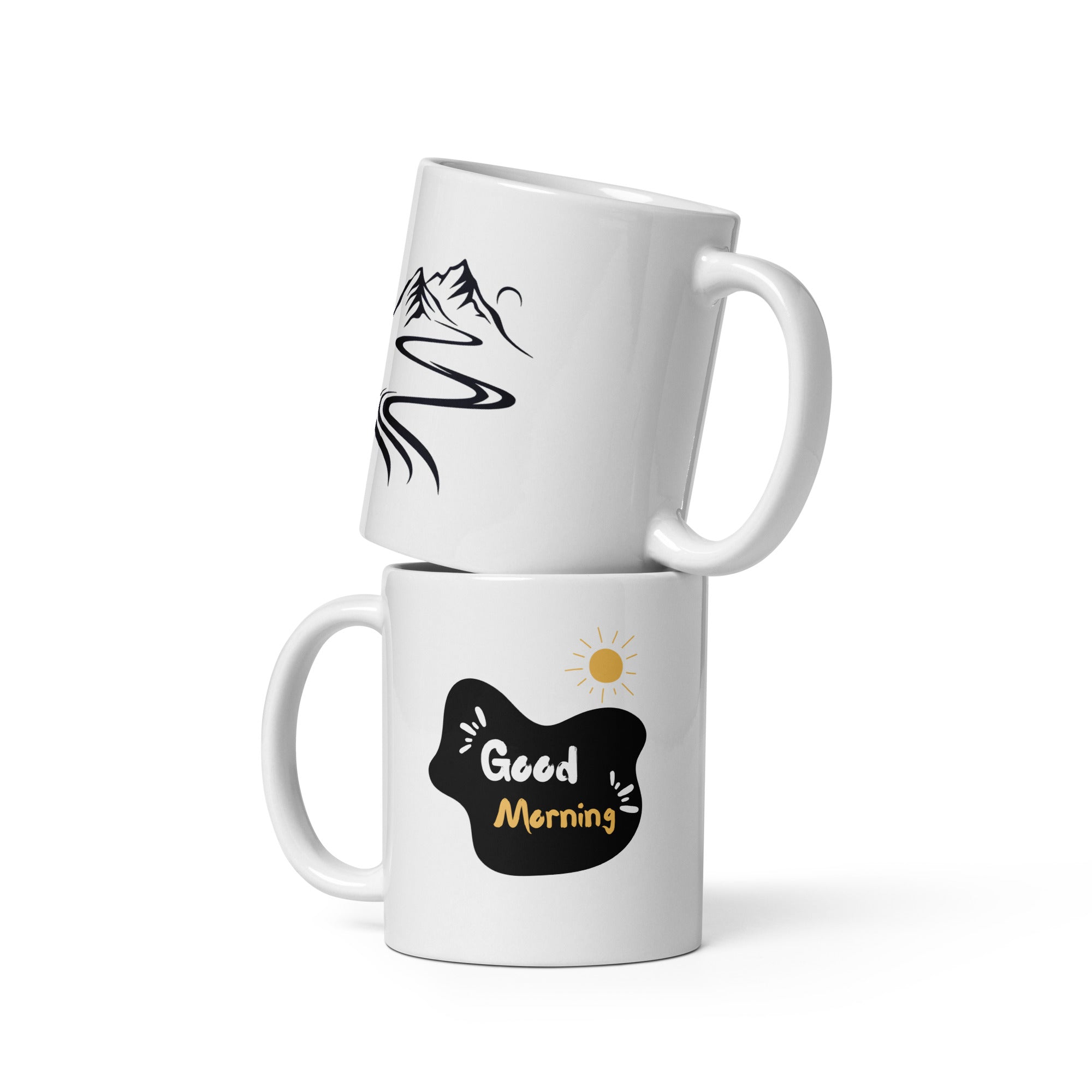 A glossy white ceramic mug with a mountain path design and a text 'GOOD MORNING' on the other side, placed against a plain background.