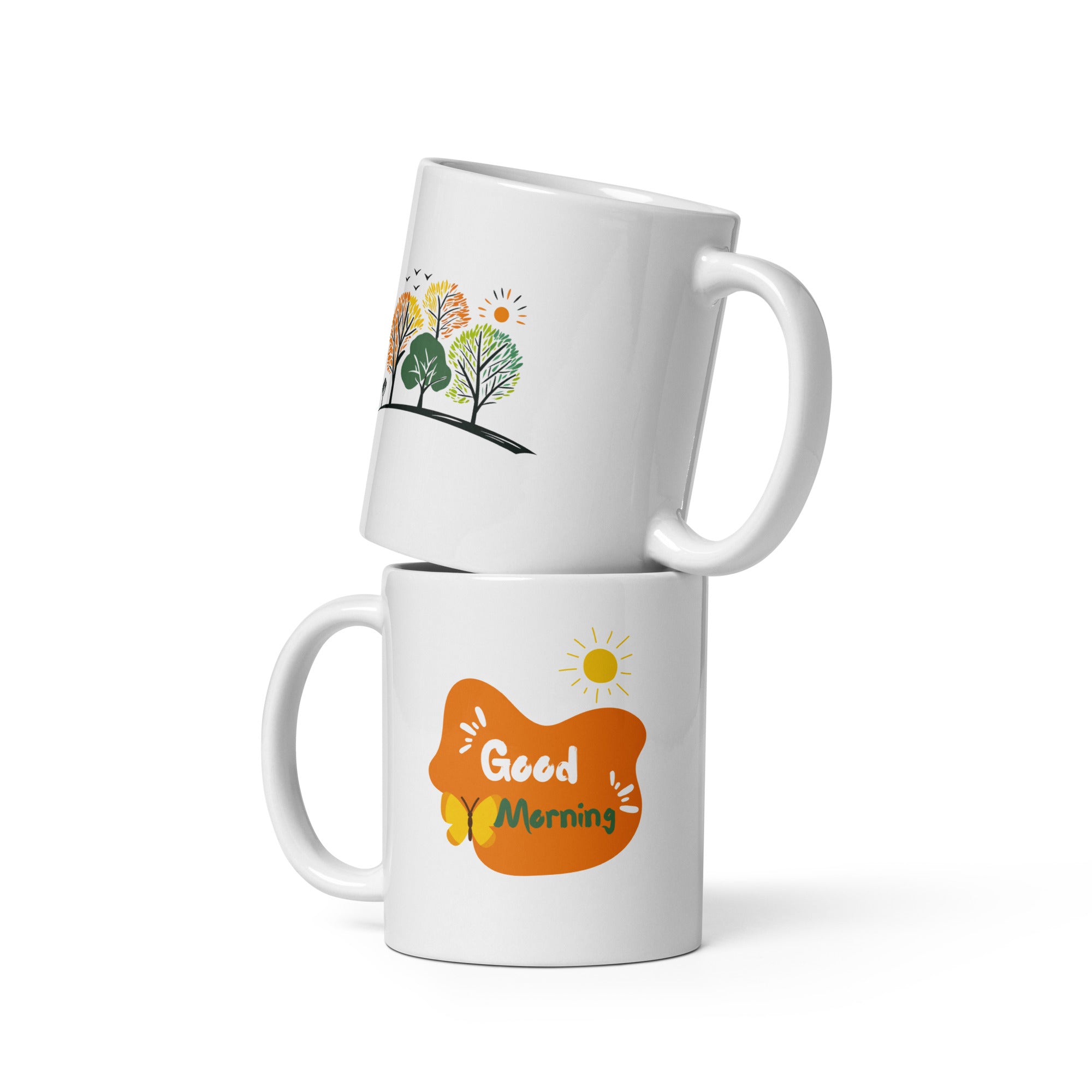 Two ceramic mugs with nature-inspired designs. One mug displays a colorful forest scene with trees and the sun, while the other mug has a 'Good Morning' message with a sun and coffee-related graphics.
