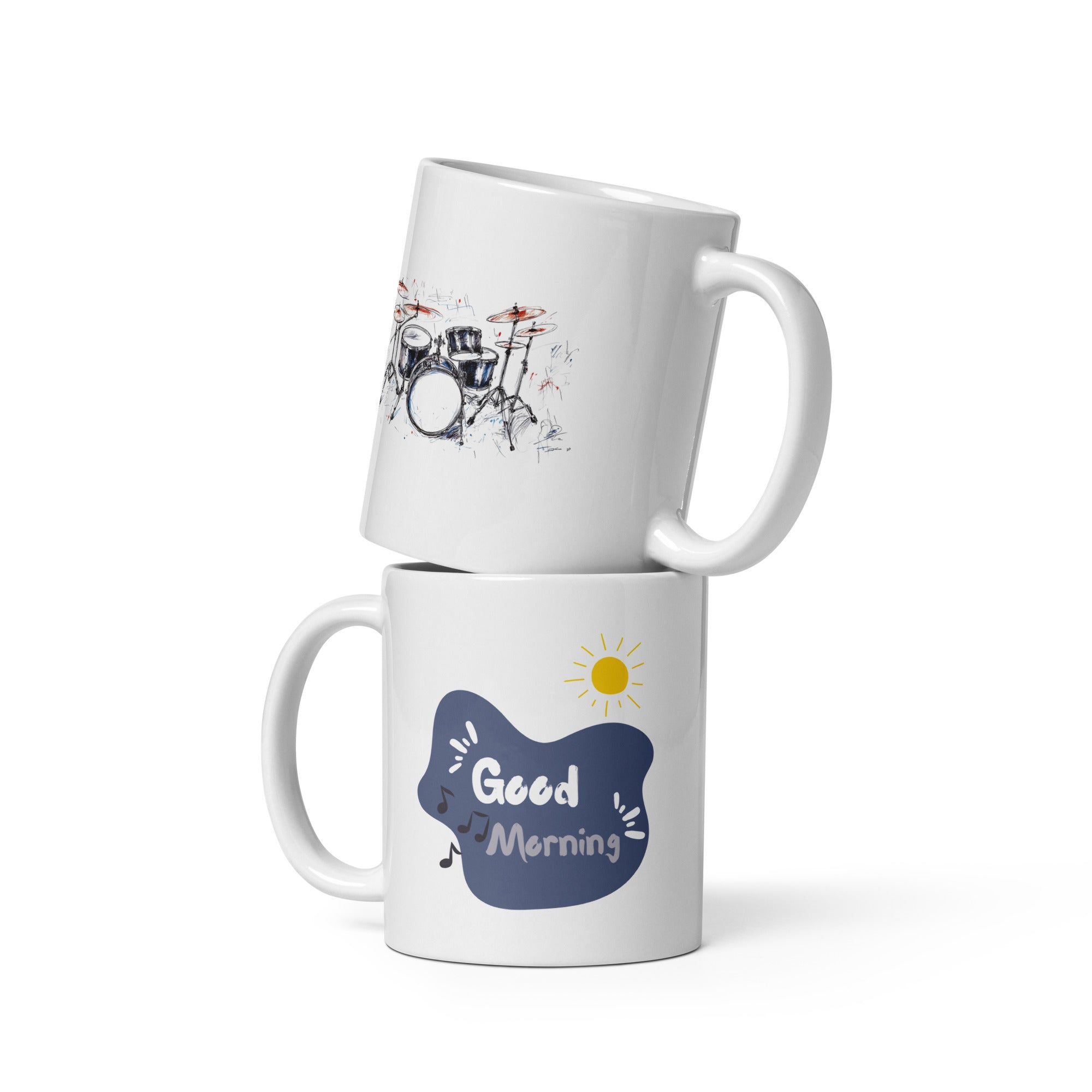 Two ceramic mugs side by side; one with a sketch of a drum kit primarily in black, white, and red, and the other with a 'Good Morning' message in a blue cloud, featuring a sun icon and musical notes.