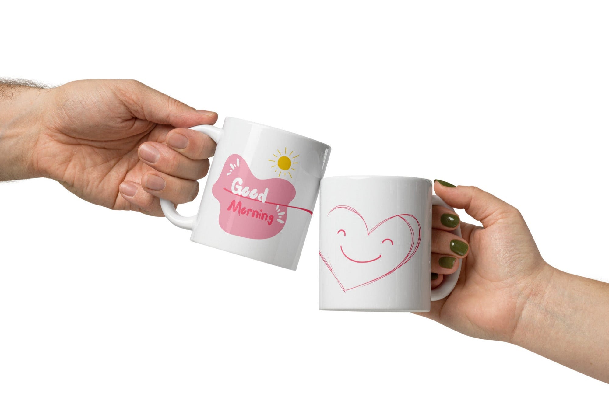 Two ceramic coffee mugs, one with a smiling heart design on the front and the other with a 'Good Morning' message alongside a sun graphic on the front. Both mugs have a white background with text and heart illustrations.