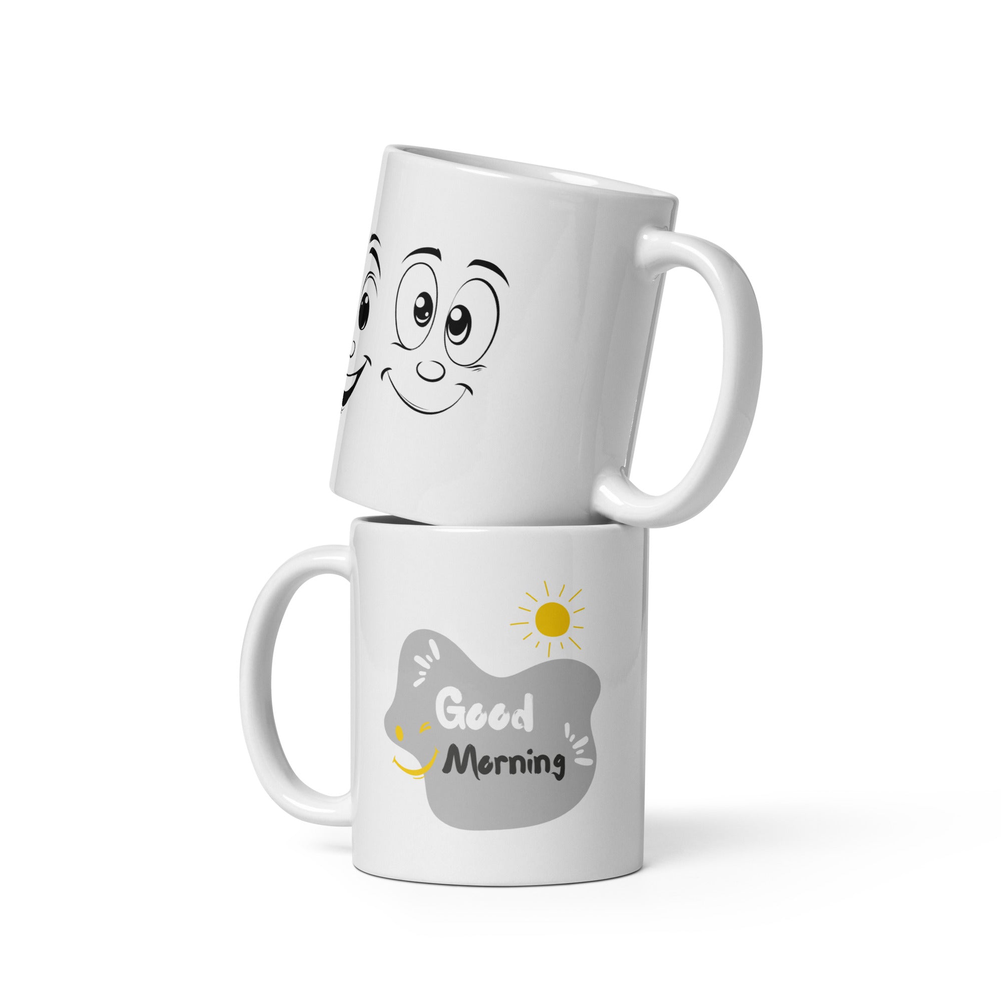 Two ceramic coffee mugs, one with a smiling face design and 'Good Morning' text, the other with a sun and 'Good Afternoon' text. Both have a white background with decorative elements.