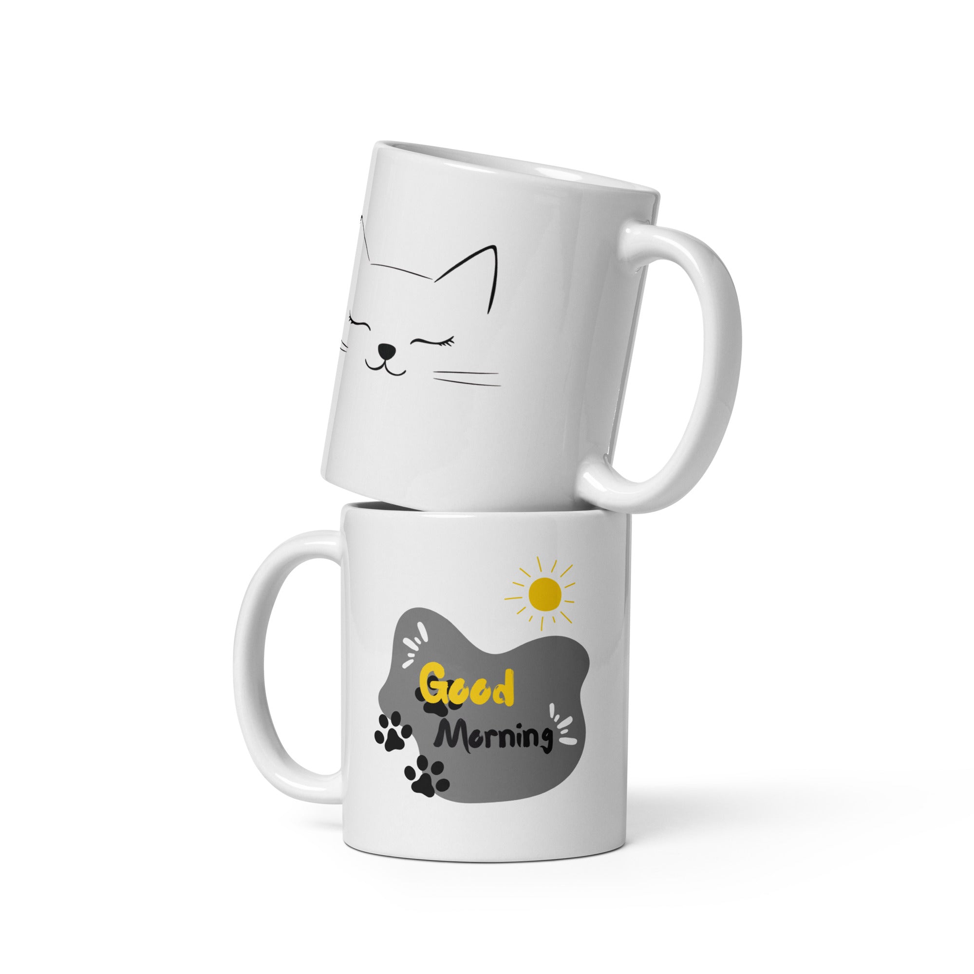 Two ceramic coffee mugs, one with a cat face illustration and 'Good Morning' text, the other with a sun design and 'Good Morning' text. Both have white interiors.