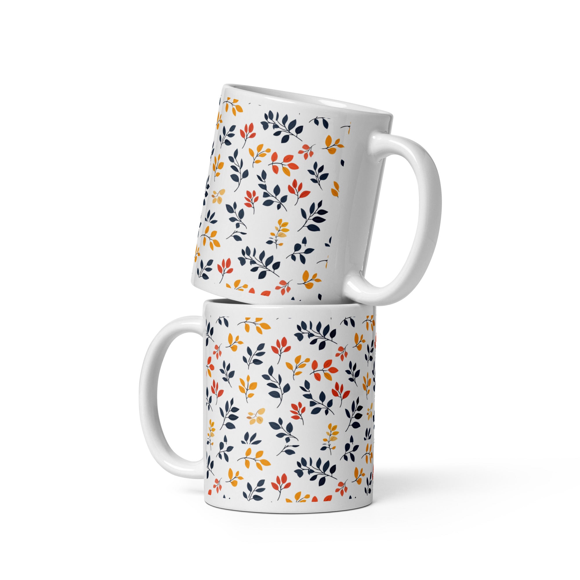 A set of two ceramic coffee mugs with a floral and autumn leaf design on a white background, one mug is filled with a liquid, possibly coffee or tea.